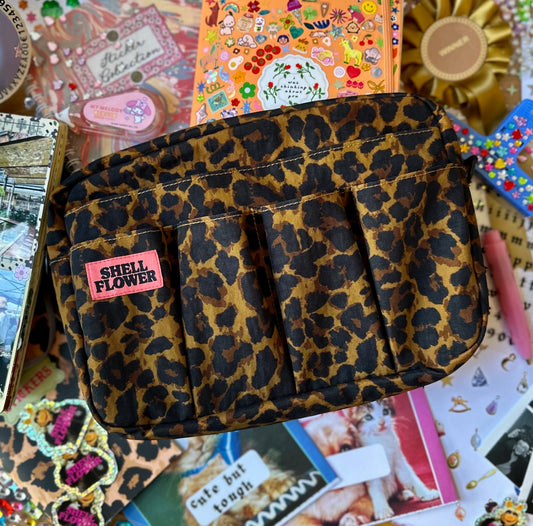 Leopard print pouch with 'Shell Flower' label on a collage background