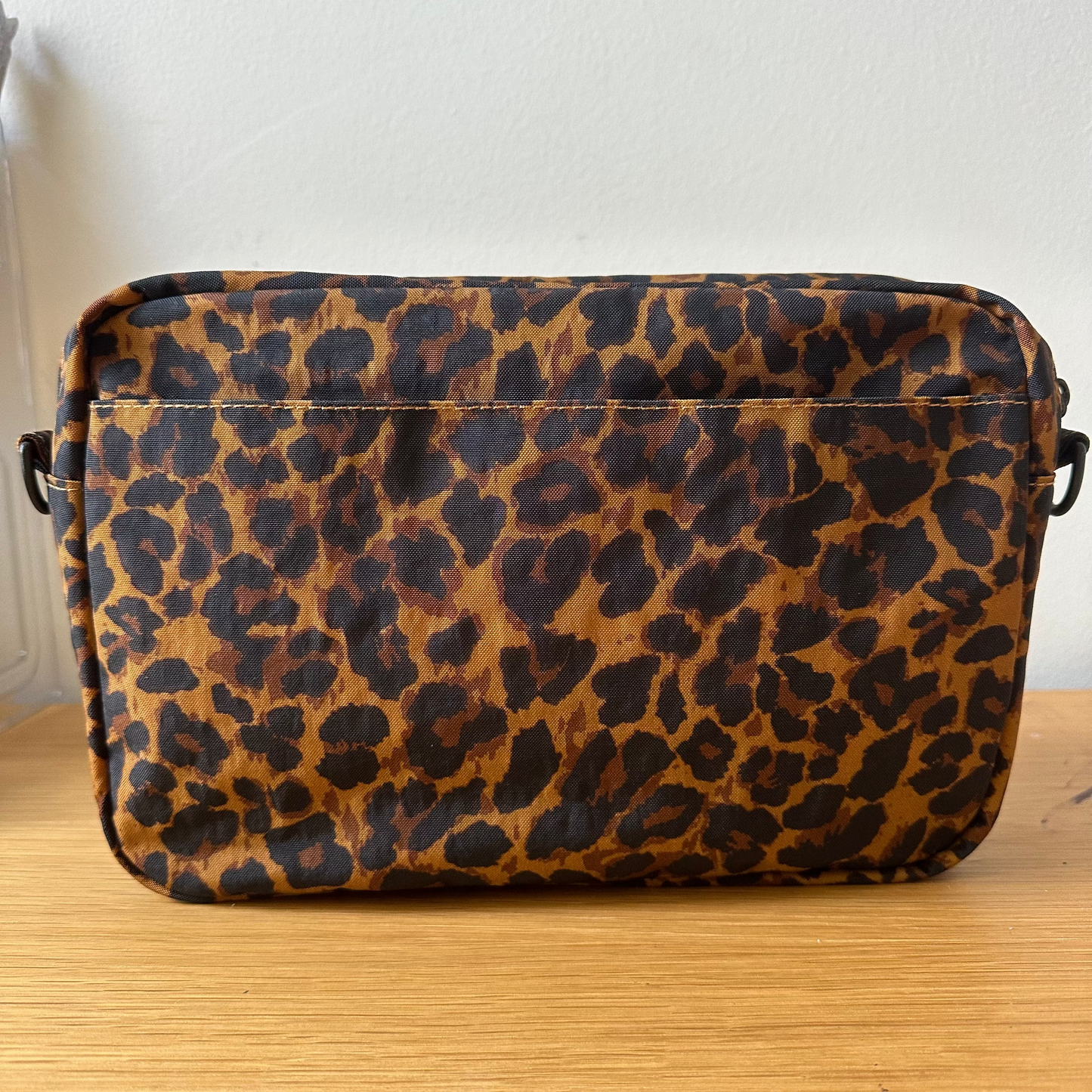 Leopard print bag on a wooden surface with a white wall background