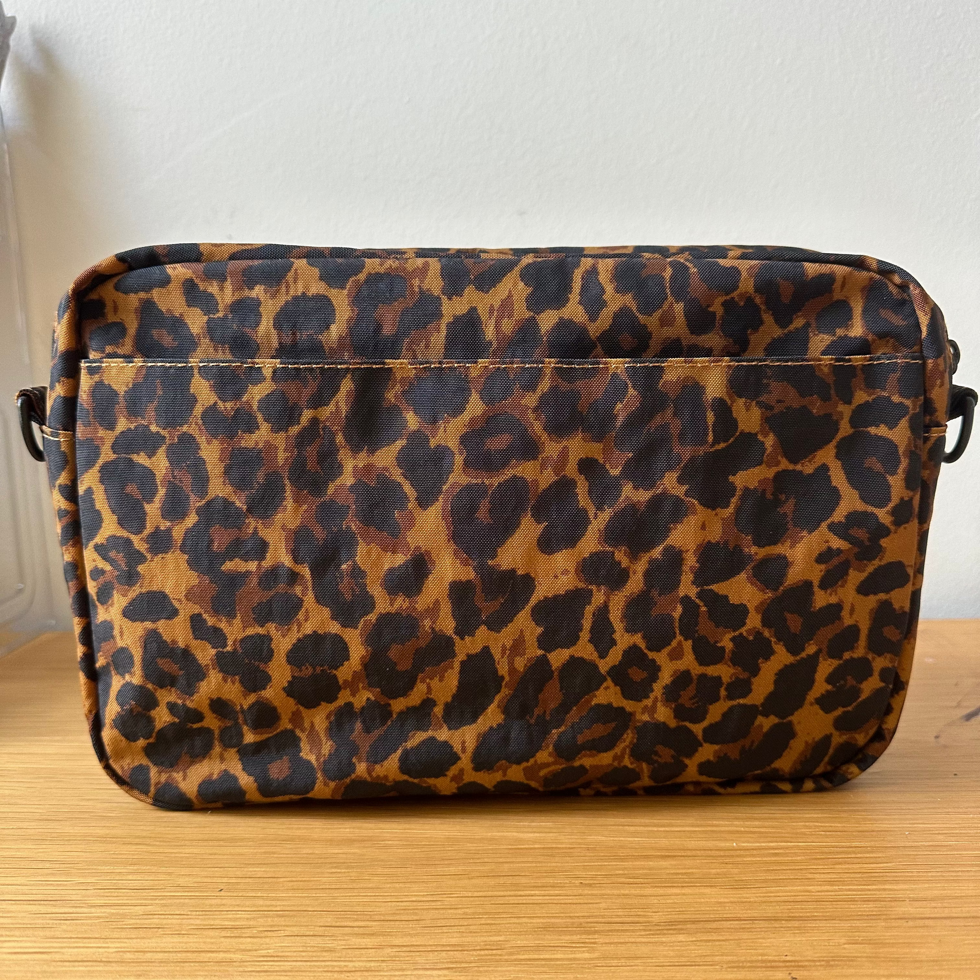 Leopard print bag on a wooden surface with a white wall background