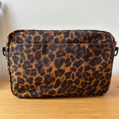 Leopard print bag on a wooden surface with a white wall background