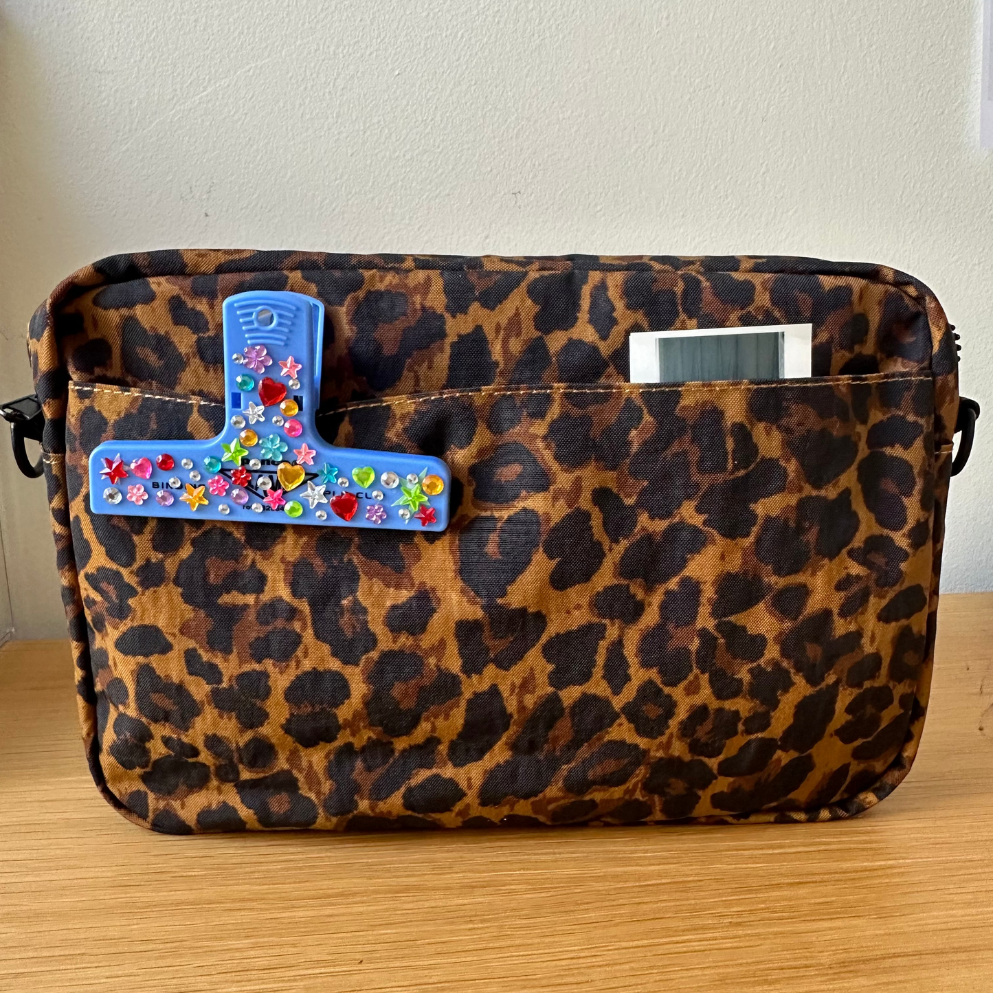 Leopard print bag with colorful decorative elements on a wooden surface