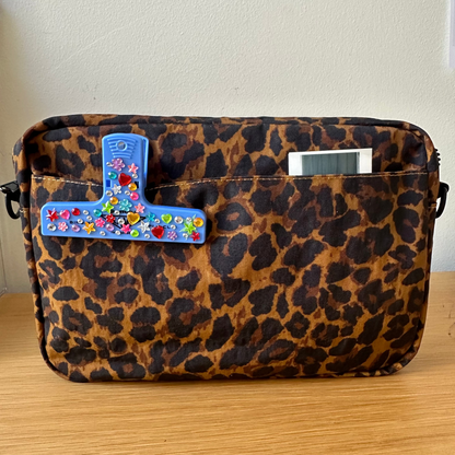 Leopard print bag with colorful decorative elements on a wooden surface